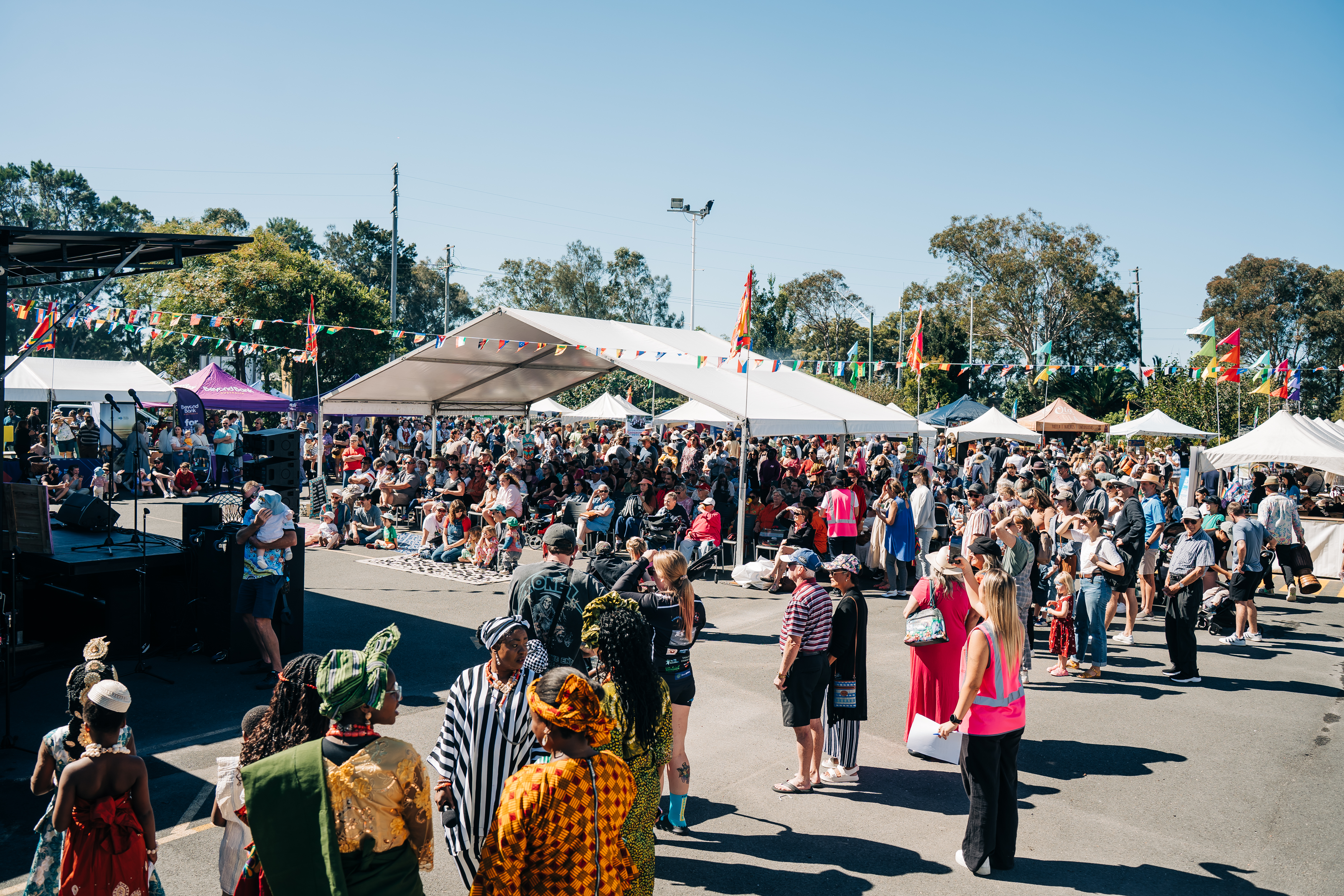 Large outdoor community festival with marquees, stage, and crowds at HMC